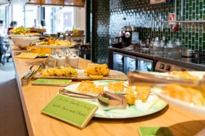 a buffet line with plates of food in a restaurant at The Editory Garden Porto Hotel in Porto