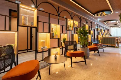 a lobby with orange chairs and tables and chairs at The Editory Garden Porto Hotel in Porto