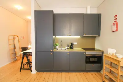 a kitchen with gray cabinets and a table in a room at Virtudes Irresistible Getaway in Porto