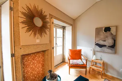 a living room with a fireplace and a chair at Virtudes Irresistible Getaway in Porto