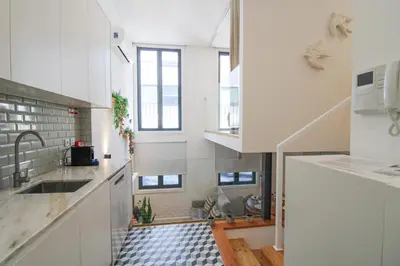 a kitchen with white cabinets and a black and white tile floor at Porto Trindade Triplex in Porto