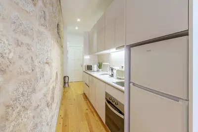 a kitchen with white cabinets and a refrigerator at Riverside Cozy Studio by LovelyStay in Porto