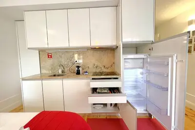 a kitchen with white cabinets and a refrigerator at Caldeireiros Lovely Suite by Porto City Hosts in Porto