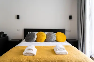a bed with yellow and grey pillows and towels on it at Almada Downtown 203 in Porto