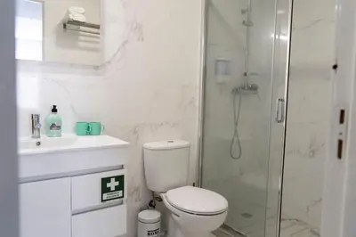a white bathroom with a toilet and a shower at Almada Downtown 204 in Porto