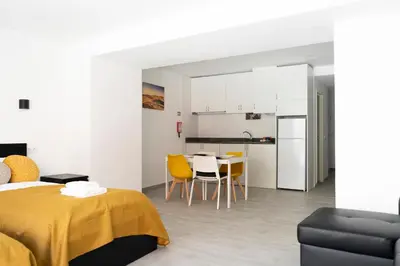 a room with a bed and a table and a kitchen at Almada Downtown 204 in Porto
