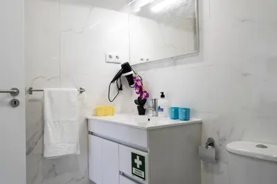 a white bathroom with a sink and a mirror at Almada Downtown 303 in Porto