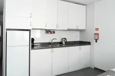 a white kitchen with a sink and a refrigerator at Almada Downtown 401 in Porto