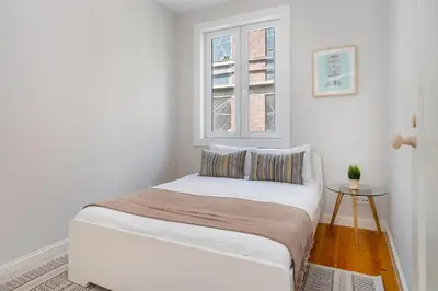 a small white bedroom with a bed and a window at Whome Formosa #2 - Central 2-Bed in Prime Location Perfect to Explore Porto in Porto