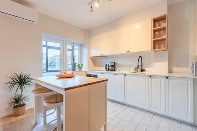 a kitchen with white cabinets and a island with stools at Enjoy Bonfim Central 2BR Renovated Apartment by LovelyStay in Porto
