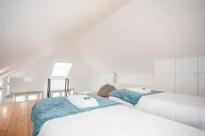 two beds in a room with white walls and wooden floors at Liiiving in Porto - Heart of Porto Mezzanine in Porto