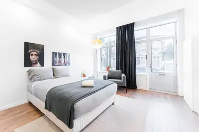 a white bedroom with a large bed and a chair at GuestReady - Uptown suites in Porto