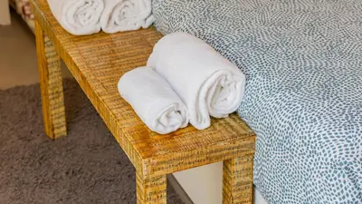 two towels on a wicker bench next to a bed at Aposentus - Stylish Downtown Loft in Porto