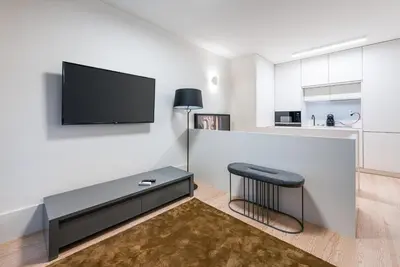 a living room with a stool and a tv on a wall at Door 65 - Historical Center Apartments in Porto