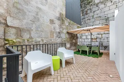a patio with white chairs and tables and an umbrella at Door 65 - Historical Center Apartments in Porto