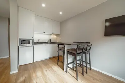 a kitchen with white cabinets and a table with stools at Crystal Palace Garden Stylish Apartment by Vacationy in Porto