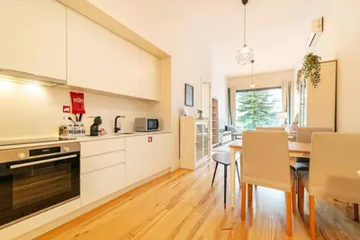 a kitchen and dining room with white cabinets and a table at Republica I by Innkeeper in Porto