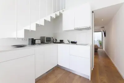 a white kitchen with white cabinets and a staircase at RIBEIRA FLORES 59 Downtown Apartments in Porto