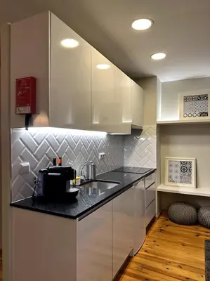 a kitchen with white cabinets and a black counter top at Almada One in Porto