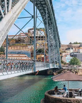 a bridge over a river with people sitting at tables at Serpa Downtown Gaia in Vila Nova de Gaia