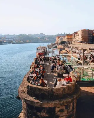 a group of people sitting on a pier next to the water at Serpa Downtown Gaia in Vila Nova de Gaia