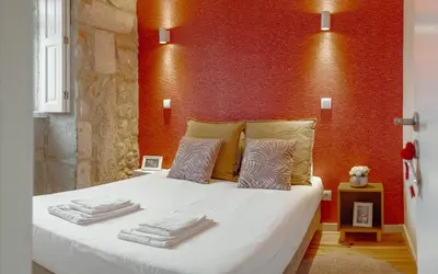 a bedroom with a white bed with a red wall at Oporto Pool Apartment by Vacationy in Porto