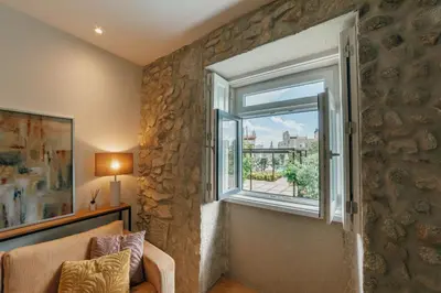 a living room with a stone wall and a window at Oporto Pool Apartment by Vacationy in Porto
