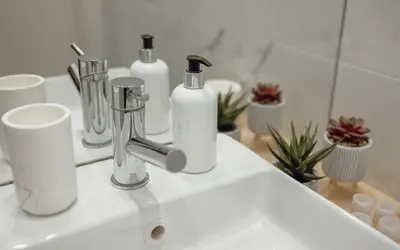 a bathroom sink with two bottles and cups on it at Oporto Pool Apartment by Vacationy in Porto