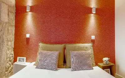 a bed with two pillows in front of a red wall at Oporto Pool Apartment by Vacationy in Porto