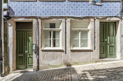 a building with green doors and windows on a street at VIVA Merchant's Way in Porto