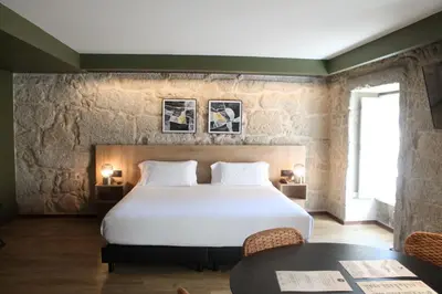a bedroom with a large bed and a table at Oca Ribeira do Porto AT in Porto