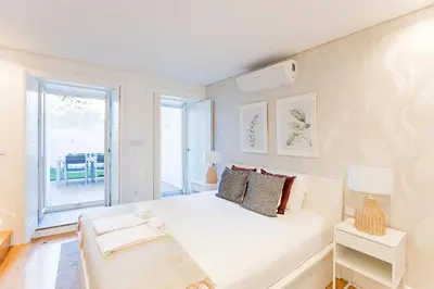 a white bedroom with a bed and a balcony at Wonderful Duplex W Private Patio & AC by LovelyStay in Porto