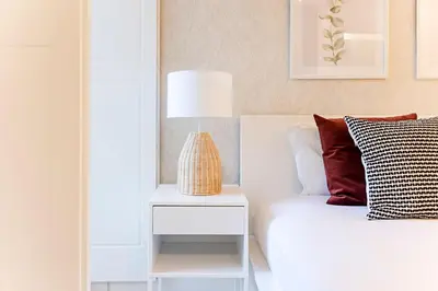 a bed with a nightstand next to a white bed with a lamp at Wonderful Duplex W Private Patio & AC by LovelyStay in Porto