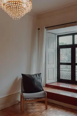 a room with a chair and a window and a chandelier at Alegria Four - Bedroom House in Porto