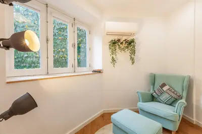 a living room with a blue chair and windows at Underground Batalha Studios in Porto