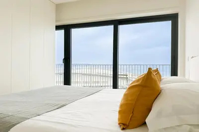 a large white bed with a yellow pillow on it at Dragão Rooftop in Porto