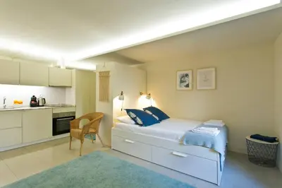 a white bedroom with a bed and a kitchen at Oporto Cozy Flats in Porto