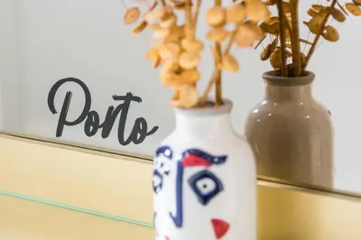 a white vase with flowers in it next to a mirror at GuestReady - Bonjardim Building in Porto