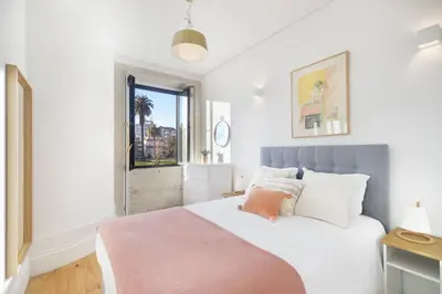 a white bedroom with a large bed and a window at República Garden View in Porto