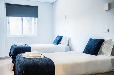 a room with two beds with blue pillows and a window at Emotions Lapa Flat in Porto