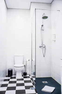 a bathroom with a toilet and a black and white checkered floor at Emotions Lapa Flat in Porto