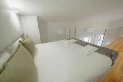 a bedroom with a white bed and a mirror at Downtown Amazing Duplex by Vacationy in Porto