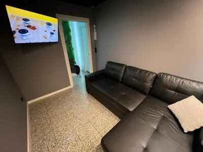a living room with a leather couch and a flat screen tv at Modern Room with Indoor Shower Near the River - Quarto Moderno com Duche interior Próximo da Ribeira in Vila Nova de Gaia