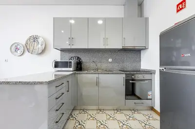 a kitchen with white cabinets and a sink and a refrigerator at Asgard Oporto Downtown Apartments in Porto