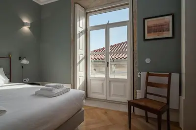 a bedroom with a bed and a window and a chair at Victoria Luxury Apartment, Historic House Downtown in Porto