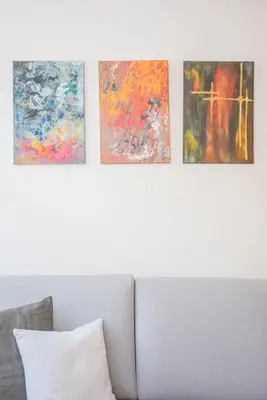 a row of paintings on a wall above a bed at Liiiving in Porto-Mouzinho Residence Apartments in Porto