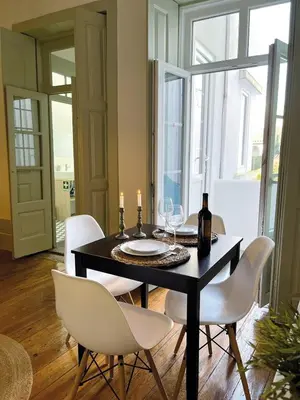 a dining room with a black table and white chairs at Porto InLapa Apartment II Terrace in Porto