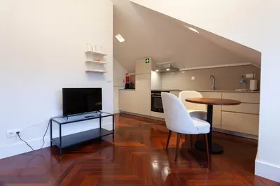 a living room with a table and chairs and a kitchen at Trindade - Loft apartment in Porto