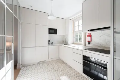 a white kitchen with white cabinets and a window at GuestReady - Porto Wine District Penthouse in Vila Nova de Gaia