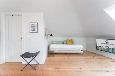a white bedroom with a bed and a chair at GuestReady - Spacious and modern Apt W/ Skylight in Porto